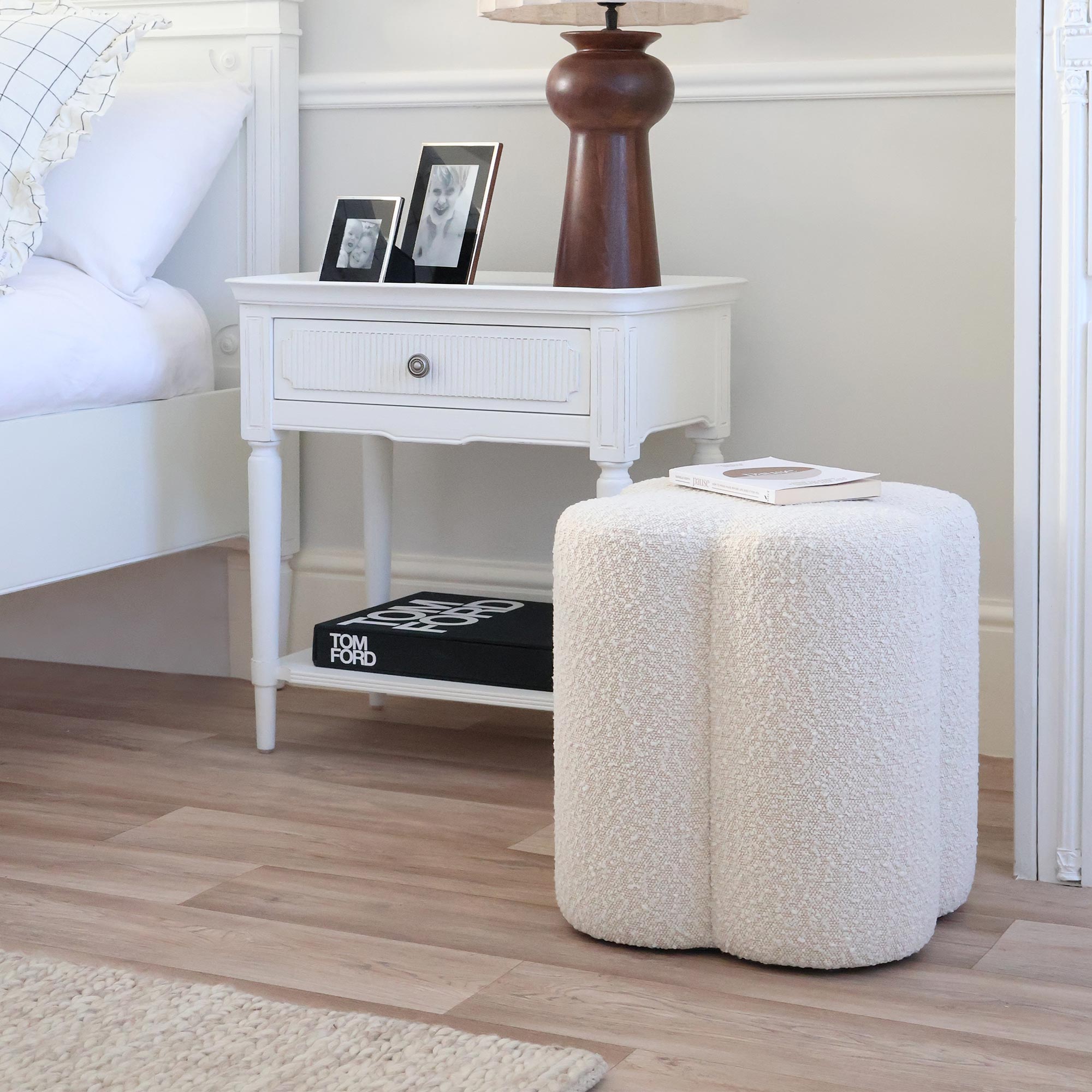 ivory clover pouffe with white bedside table and bed 
